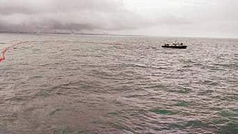 Boom barriers are placed around the sinking ship to contain possible oil spill