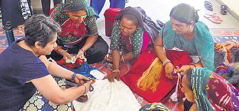 A group of women being taught different kinds of embroidery