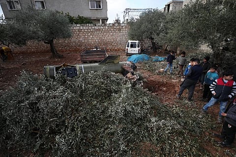 People gather around the remains of a missile, fired by Syrian regime forces, in a field in the town of Sarmeen (Photo| AFP)