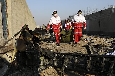 Rescue workers carry the body of a victim of an Ukrainian plane crash among debris of the plane in Shahedshahr, southwest of the capital Tehran, Iran. (Photo | AP)