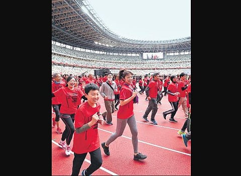 Volunteers run at New National Stadium during a promotional event in Tokyo.