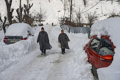 Men walk on a snow-covered road after heavy snowfall at Ferozpora village of Tangmarg in Baramulla district of north Kashmir Wednesday Jan. 15 2020. (Photo | PTI)