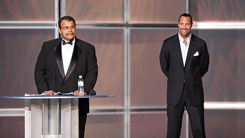 Rocky 'Soul Man' Johnson, left, speaks at his WWE Hall of Fame induction ceremony, as his son, Dwayne “The Rock” Johnson watches. (Photo | AP)