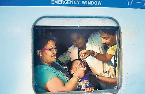 Health department workers administer Pulse Polio vaccine to a child on a train, as it stopped at KSR Station, in Bengaluru on Sunday (Photo | Pandarinath B, EPS)