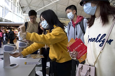 Travelers wearing face masks gather at Hong Kong International Airport in Hong Kong. (Photo | AP)