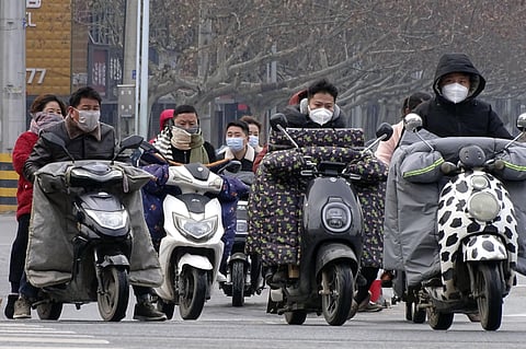 Scooter drivers wear face masks as they wait to cross an intersection in Fuyang in central China