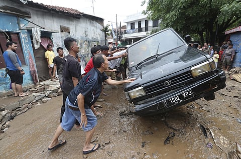 Residents move the wreckage of cars that were swept away by flood in Bekasi, West Java, Indonesia, Friday, Jan. 3, 2020.Severe flooding in greater Jakarta has killed scores of people and displaced tens of thousands others, the country's disaster managemen