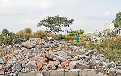 The houses demolished on the Hulimavu Lake bed as part of BBMP’s encroachment clearance drive on Thursday; (below) a man shows a marked property during the drive | Meghana Sastry