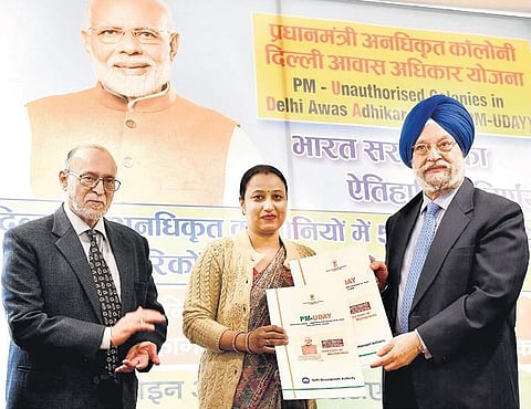 Minister of State for Housing & Urban Affairs Hardeep Singh Puri hands over the conveyance deeds and property registry papers to residents of unauthorised colonies in New Delhi on Friday. (Photo | PTI)