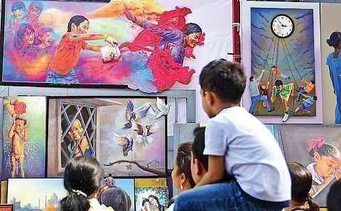 People look at some of the paintings made with a myriad of colours at Chitra Santhe, in Bengaluru on Sunday. (Photo | Shriram BN, EPS)