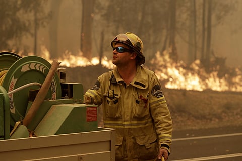 A Forest Corporation worker manages a fire hose as he battles a fire near Moruya, Australia, Saturday, Jan. 4, 2020. Australia's Prime Minister Scott Morrison called up about 3,000 reservists as the threat of wildfires escalated Saturday in at least three