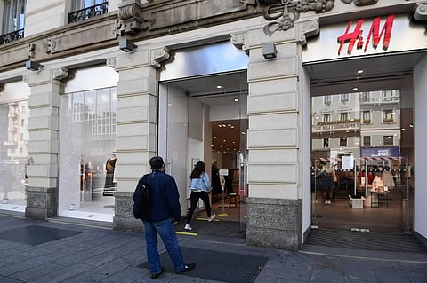People wait outside an H&M clothing shop in Milan. (Photo|AFP)