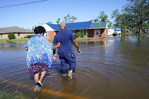 Soncia King holds onto her husband Patrick King in Lake Charles, La., Saturday, Oct. 10, 2020, as they walk through the flooded street to their home, after Hurricane Delta moved through. (Photo | AP)