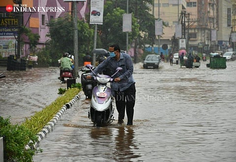 A man walking with a two wheeler on a flooded road in Vijayawada after heavy rains lash Andhra Pradesh. (Photo | EPS/Prashant Madugula)