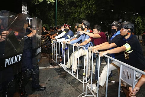 Pro-democracy protesters stand in front of Thai policemen with riot shields during a demonstration in Bangkok. (Photo | AP)
