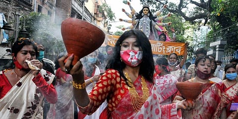 Women perform 'Dhunachi' dance on the arrival procession of Goddess Durga idol at their community puja pandal ahead of 'Durga Puja' festival amid coronavirus pandemic in Kolkata. (Photo | PTI)