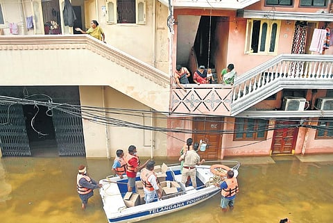 TRS Corporator Vijaya Reddy distributes food packets to residents, who have been marooned off in the floods at Khairatabad, on Thursday | RVK Rao