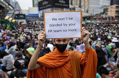 A Buddhist monk, supporter of pro-democracy movement, displays a placard during a protest rally at an intersection in Bangkok, Thailand, Sunday, Oct. 18, 2020. (Photo | AP)