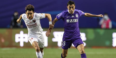 Akhmedov Odil of Tianjin Teda, right, and Zhang Yuan of Shenzhen Jiazhaoye compete for the ball during their CSL match in Dalian in northeastern China's Liaoning Province. (Photo | AP)