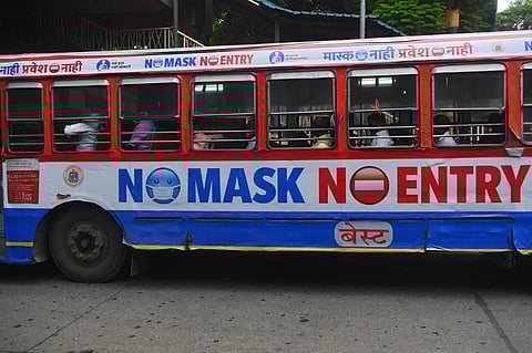 Passengers travel in a bus with a precautionary message pasted against the spread of Covid-19 coronavirus. (Photo| AFP)