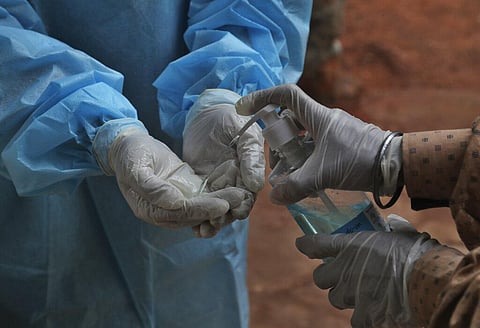 A health worker cleans her hands with sanitizer after taking a nasal swab sample from a patient at a COVID-19 testing center. (Photo | AP)