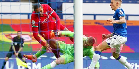 Liverpool's Virgil van Dijk is tackled by Everton's goalkeeper Jordan Pickford before leaving the match injured. (Photo | AP)