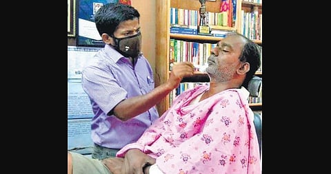 P Pon Mariappan at work in his salon cum library in Millerpuram. (Photo| Express)