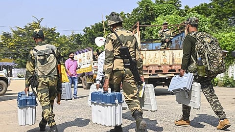 Security personnel carrying EVMs on their way to a polling booth.