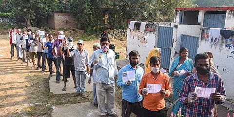 Voters show their identity cards as they stand in a queue outside a polling station at Naubatpur in Patna. (Photo | PTI)