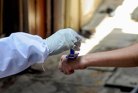 A health worker marks the hands of residents with home quarantine stamp. (Photo | PTI)