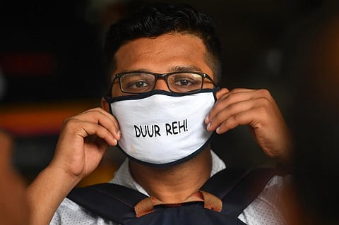 A passenger wearing a facemask reading 'Stay Away' comes out of a metro station. (File Photo| AFP)