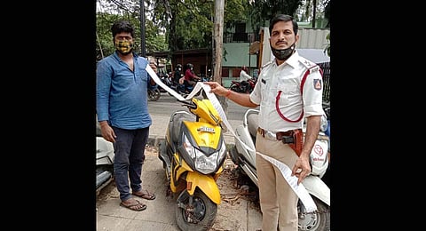 An officer with the seized scooter and the list of pending violation cases. (Photo | EPS)