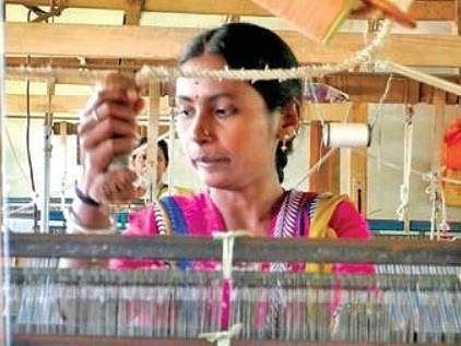 A file picture of a woman weaving fabric at Charaka before the pandemic