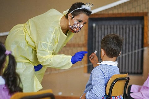Medical personnel hands over a non-invasive Covid 19 test with chewing gum to a child at the G.B. Grassi school, in Fiumicino, near Rome, Tuesday, Oct. 6, 2020. (Photo | AP)