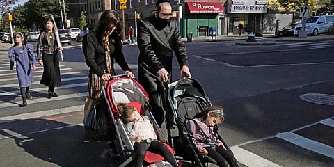 A Jewish man and woman wheel strollers with sleeping children in them as they cross a street in New York on the Jewish holiday of Sukkot. (Photo| AP)