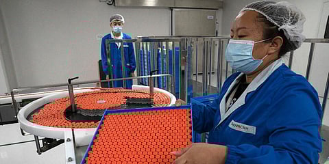 A worker feeds vials for production of SARS CoV-2 Vaccine for COVID-19 at the SinoVac vaccine factory in Beijing. (File photo| AP)