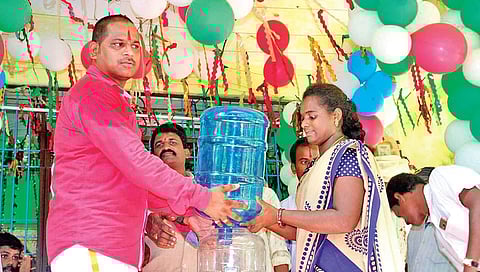 Pullata Ram Kumar distributing a water can to a woman at Bairipuram  in Srikakulam district. (File photo| EPS)