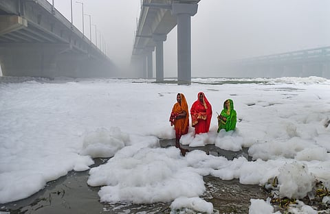 Devotees offers prayers to the rising sun as toxic foam floats on the surface of polluted Yamuna river (File photo | PTI)