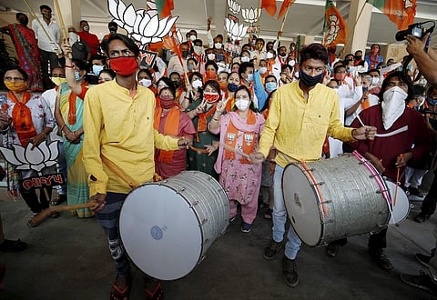 Supporters of BJP hold their party symbol and flags as they gather to celebrate after learning of the initial poll results at Gandhinagar. (Photo | PTI)