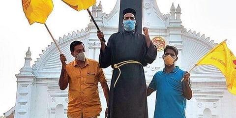 As a mark of protest, Fr Basil Kottikan ties himself to the cross in front of the St Thomas Church in Kothamangalam on Wednesday. (Photo| EPS)