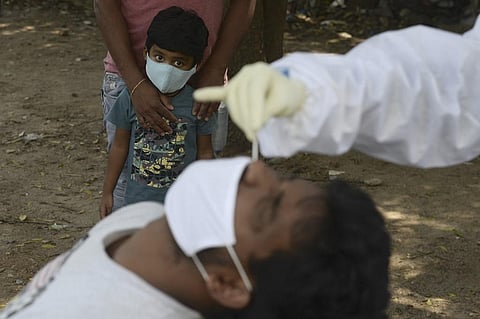 A boy watches as a health worker collects a swab sample from a man to test for the Covid-19 coronavirus. (Photo| AFP)