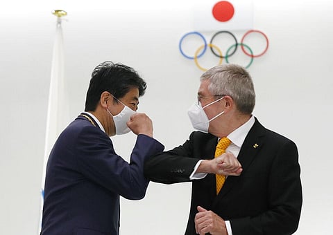 Former Japan's Prime Minister Shinzo Abe, left, and Thomas Bach, President of the International Olympic Committee (IOC), bump elbows after a ceremony to present the Olympic Order to Abe. (Photo | AP)