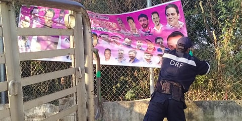 A DRF staffer removes a banner adorning a fence in the city after the election code came into force on Tuesday. (Photo| EPS)