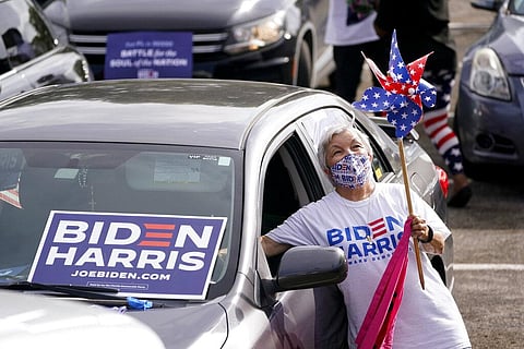 Norma Fisher reaches into her car to honk the horn as she attends a drive-in early voting event for Democratic vice presidential candidate Sen. Kamala Harris. (Photo | AP)