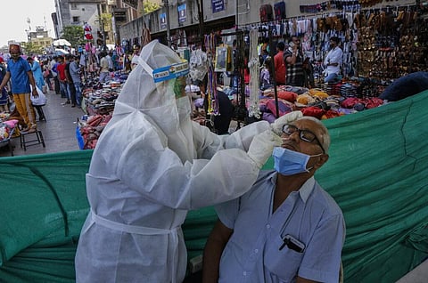 A health worker takes a nasal swab sample of a man to test for COVID-19 at a facility erected in a market in Ahmedabad, India, Tuesday, Nov. 17, 2020. (Photo | AP)