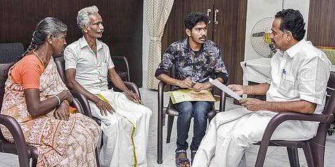 Minister MR Vijayabhaskar handing over the first term’s college fee of `20,000 to Marimuthu and his parents in Karur on Friday | Express