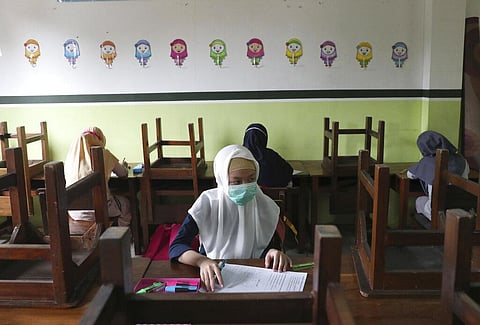 Students wearing face masks sit spaced apart during a trial run of a class with COVID-19 protocol (Photo | AP)