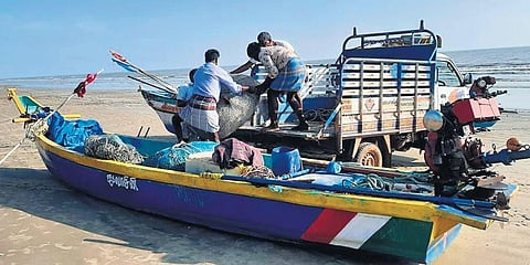 Fishermen shifting their nets and engines from a fiberglass boat to safe place in a coastal village near Vedaranyam.