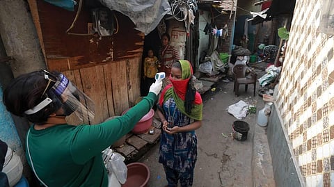 SDMC personals reads the temperature of a woman during a door to door survey to assess the COVID-19 situation at Raghubir nagar slum area in New Delhi. (Photo | Shekhar Yadav/EPS)