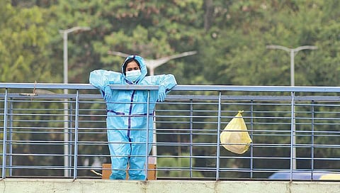 A medical worker in a PPE suit takes a break at Majestic Bus Stand | ASHISHKRISHNA HP